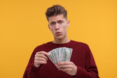 Photo of Handsome man with dollar banknotes on yellow background