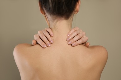 Photo of Back view of woman with perfect smooth skin on beige background, closeup. Beauty and body care