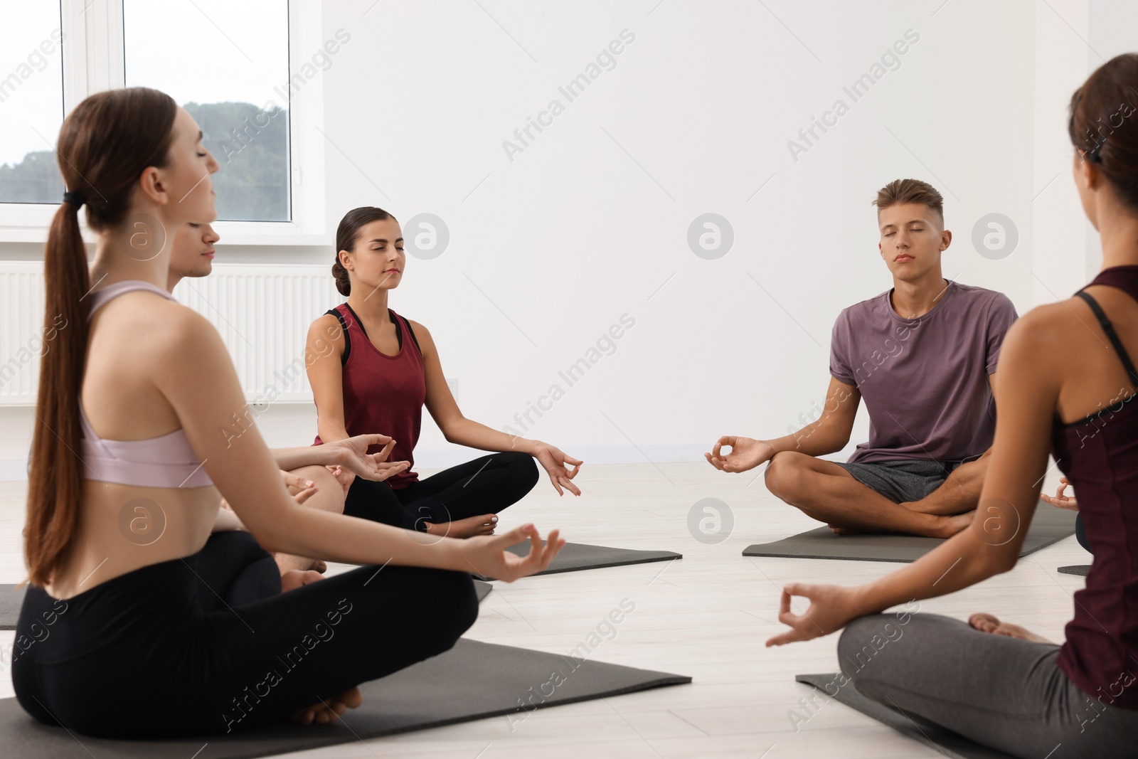 Photo of Group of people practicing yoga on mats indoors