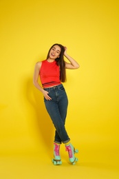 Full length portrait of young woman with roller skates on color background