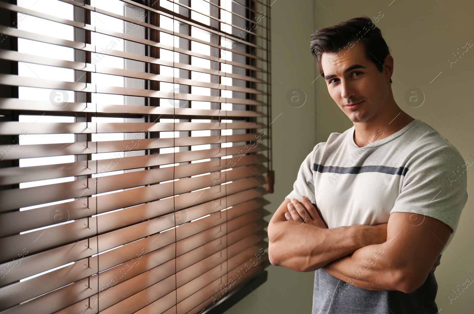 Photo of Handsome young man standing near window indoors