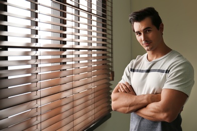 Photo of Handsome young man standing near window indoors