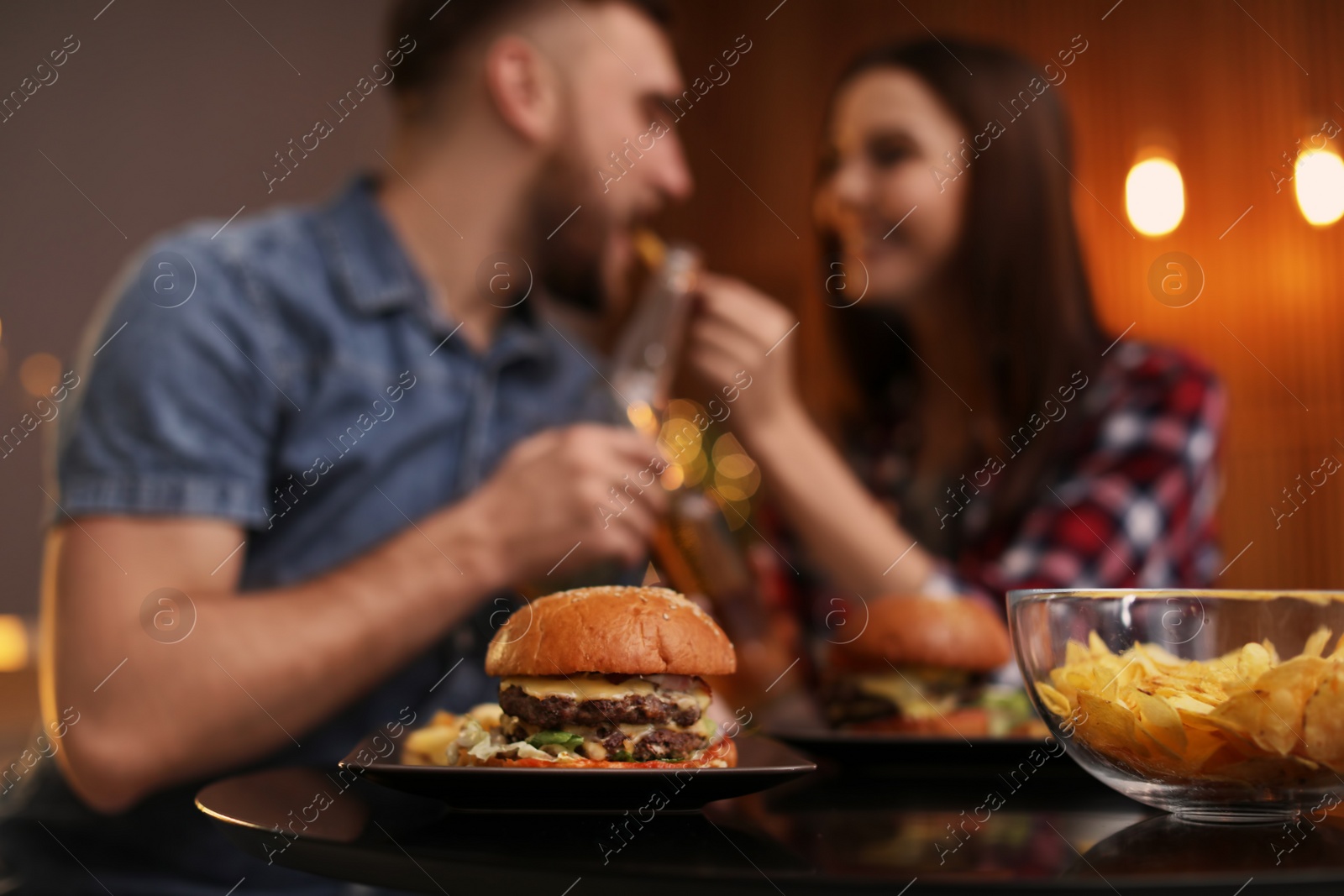 Photo of Happy couple having lunch in cafe, focus on burger
