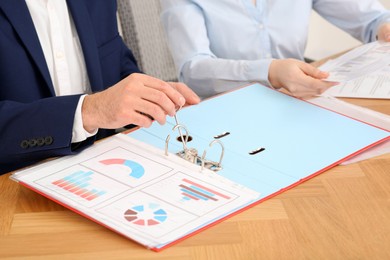 Photo of Businesspeople working with charts at wooden table in office, closeup