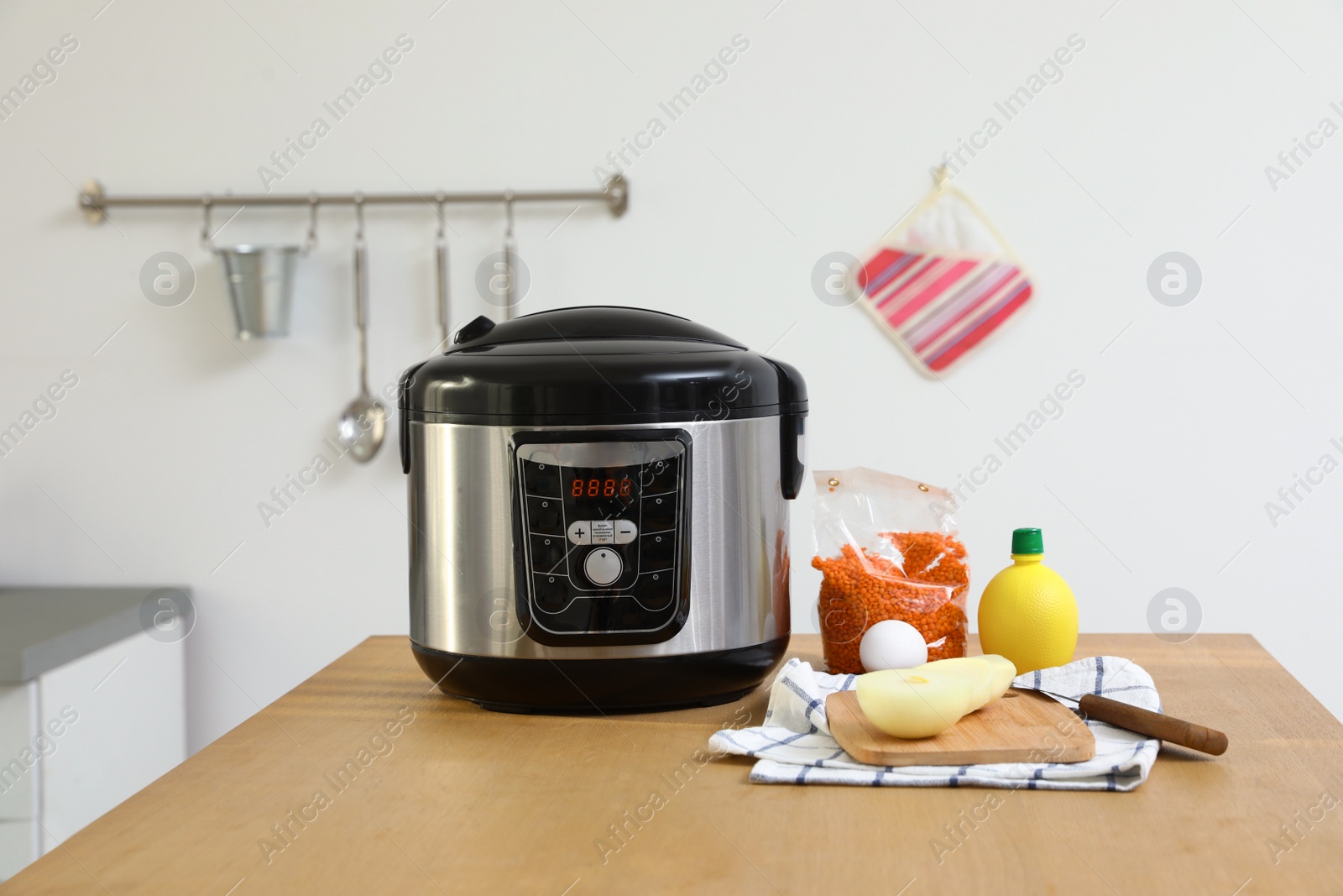 Photo of New modern multi cooker and products on table in kitchen