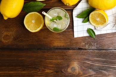 Cool freshly made lemonade and fruits on wooden table, flat lay. Space for text