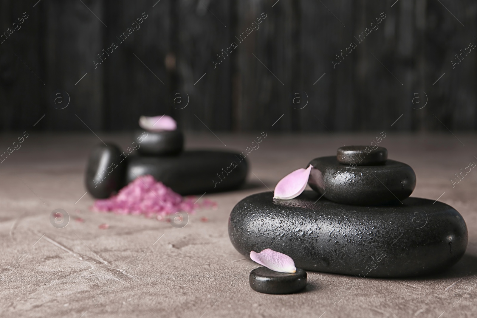 Photo of Spa stones and flower petals on table. Space for text