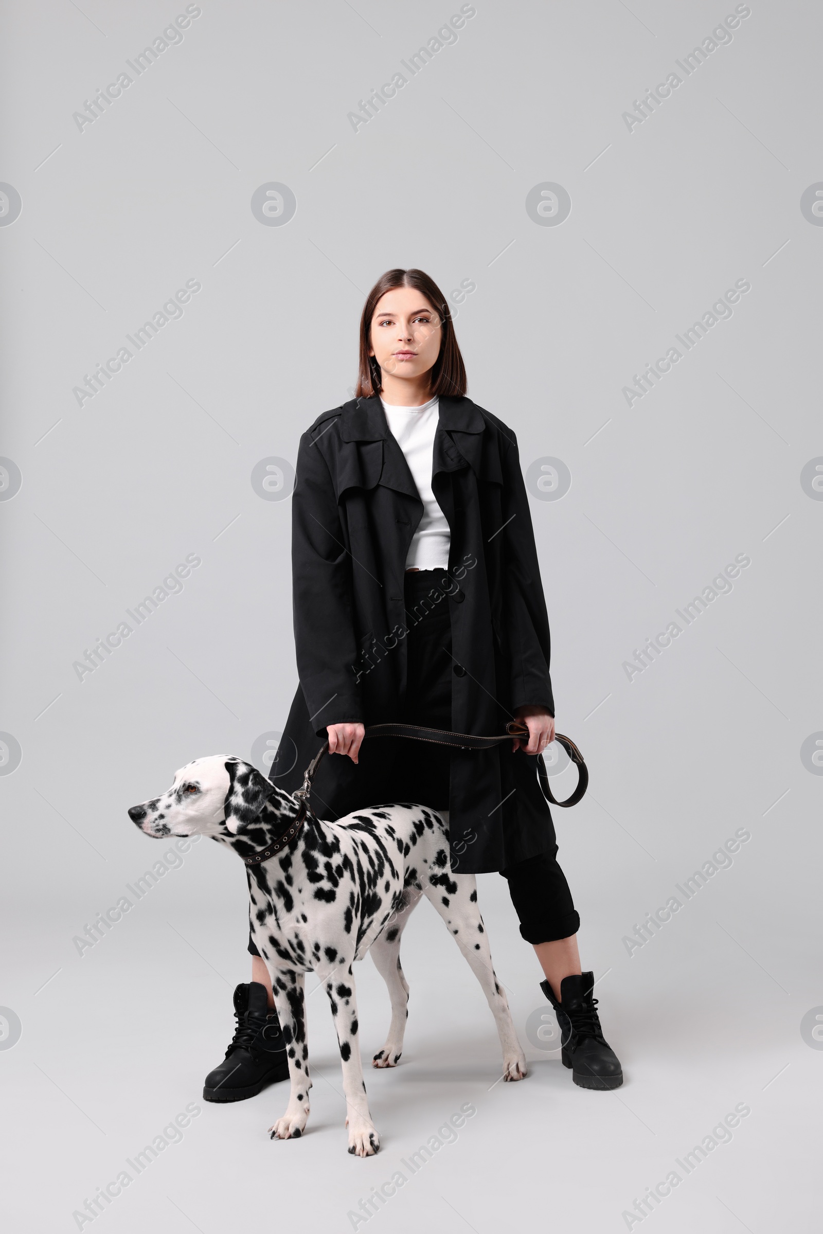 Photo of Beautiful young woman with her adorable Dalmatian dog on light grey background. Lovely pet