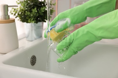 Woman washing glass at sink in kitchen, closeup