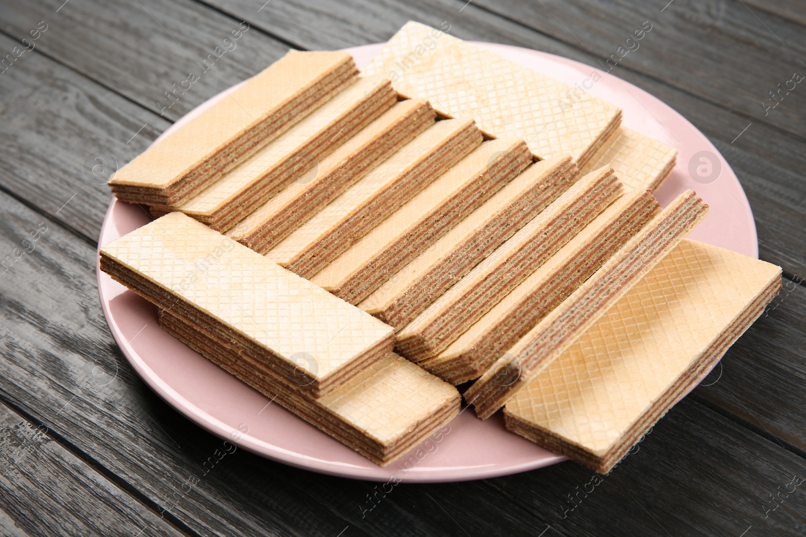 Photo of Plate with delicious crispy wafers on wooden table