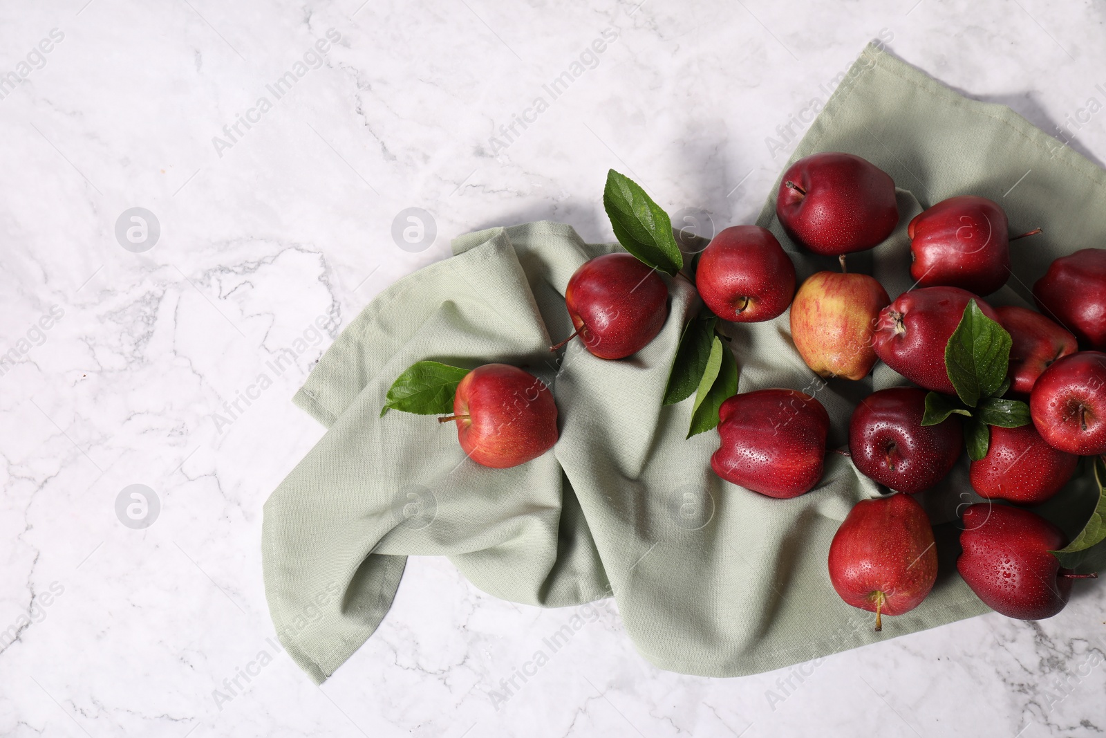 Photo of Fresh ripe red apples with leaves on white marble table, flat lay. Space for text