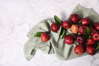 Photo of Fresh ripe red apples with leaves on white marble table, flat lay. Space for text