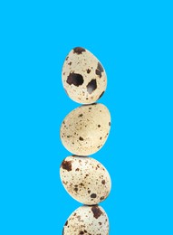 Image of Stacked speckled quail eggs on light blue background