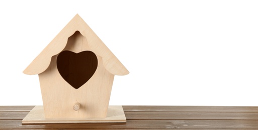 Beautiful bird house with heart shaped hole on wooden table against white background, space for text