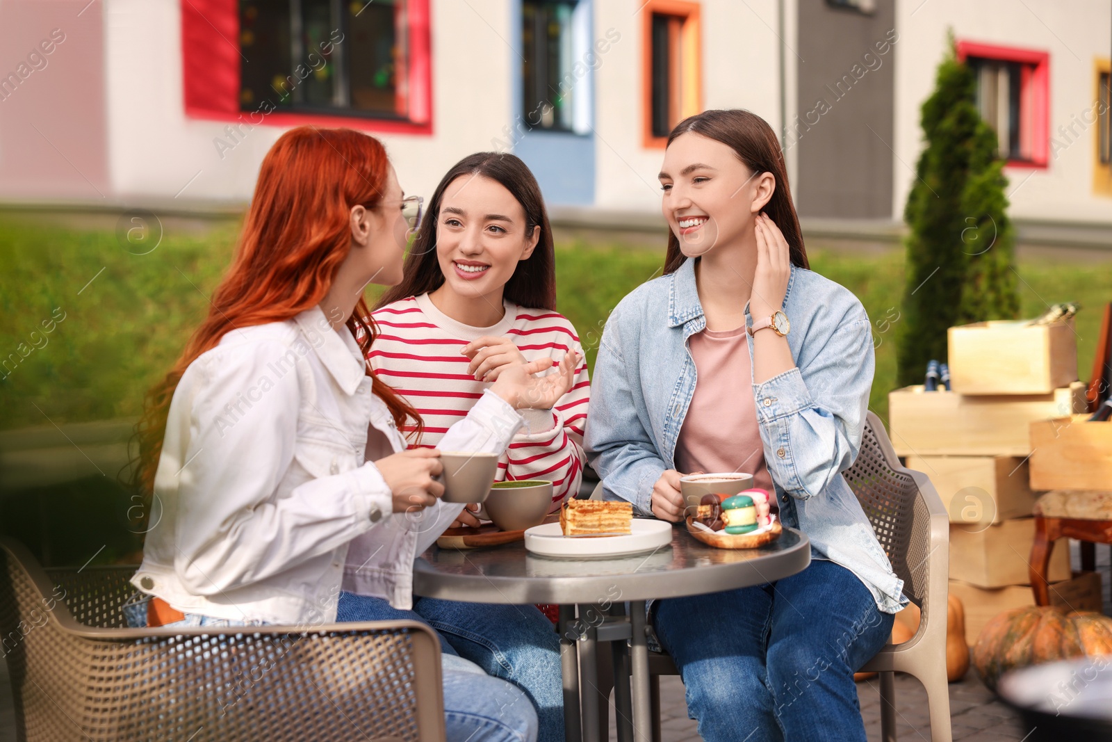 Photo of Happy friends talking and drinking coffee in outdoor cafe