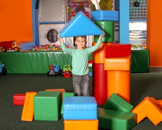 Cute child playing with colorful building blocks indoors