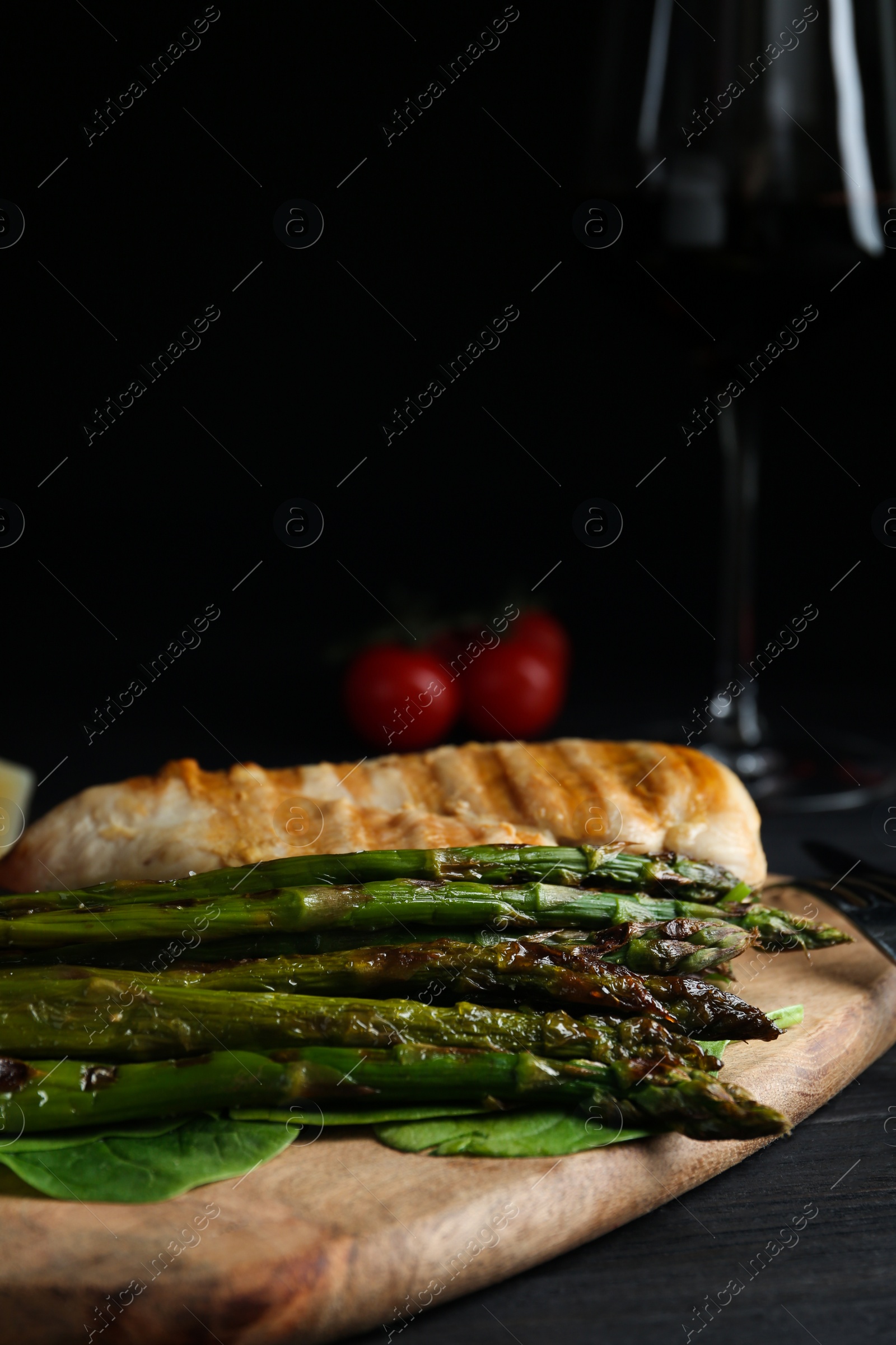 Photo of Tasty grilled chicken fillet served with asparagus on wooden board