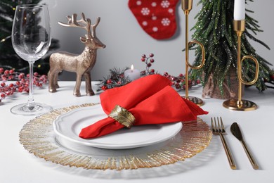 Photo of Plates with red fabric napkin, cutlery and festive decor on white table