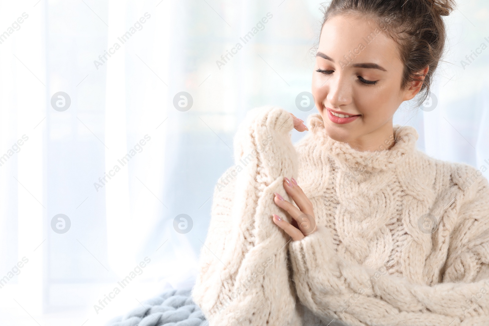 Photo of Portrait of beautiful teenage girl in warm cozy sweater on light background. Space for text