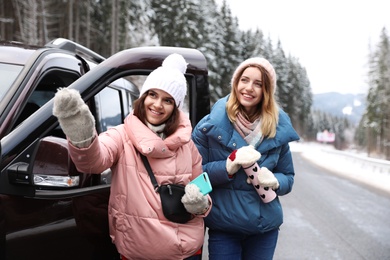 Photo of Friends standing near car on road. Winter vacation