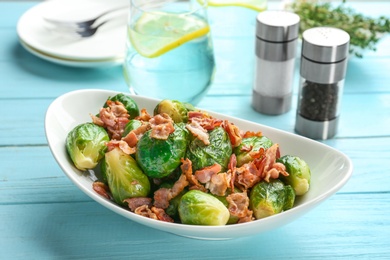 Photo of Tasty roasted Brussels sprouts with bacon on light blue wooden table