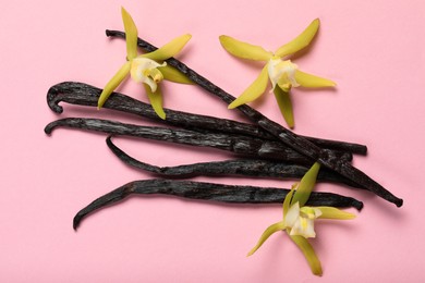 Photo of Vanilla pods and beautiful flowers on pink background, top view
