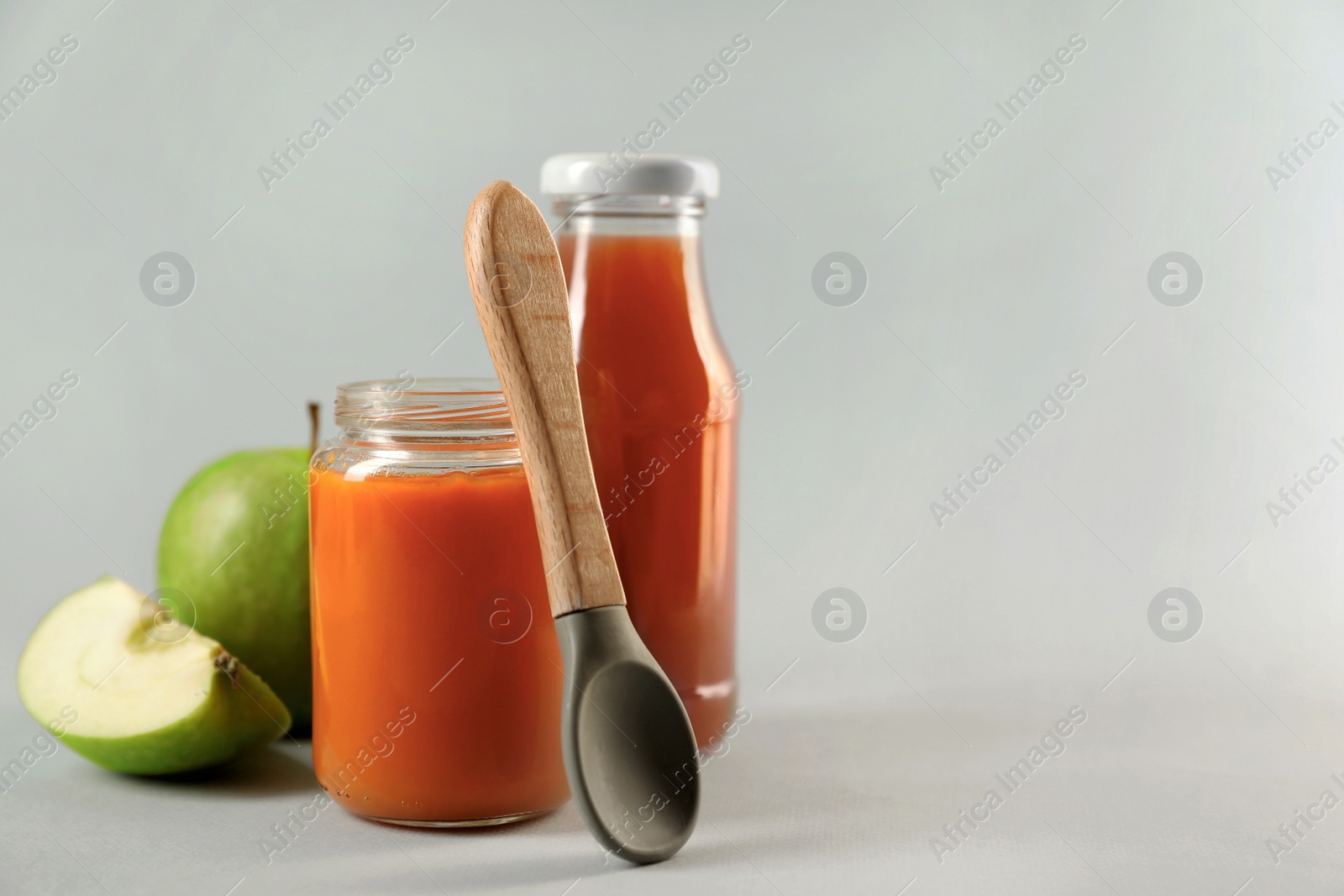 Photo of Healthy baby food, apple, juice and spoon on white background, space for text