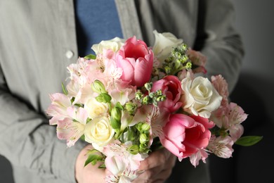 Photo of Man holding bouquet of beautiful flowers indoors, closeup