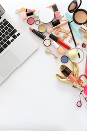 Flat lay composition with makeup products for woman and laptop on white background