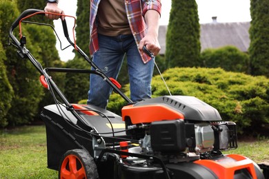 Man with modern lawn mower in garden, closeup