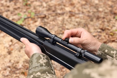 Man with hunting rifle wearing camouflage outdoors, closeup