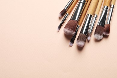 Photo of Set of makeup brushes on beige background, above view. Space for text