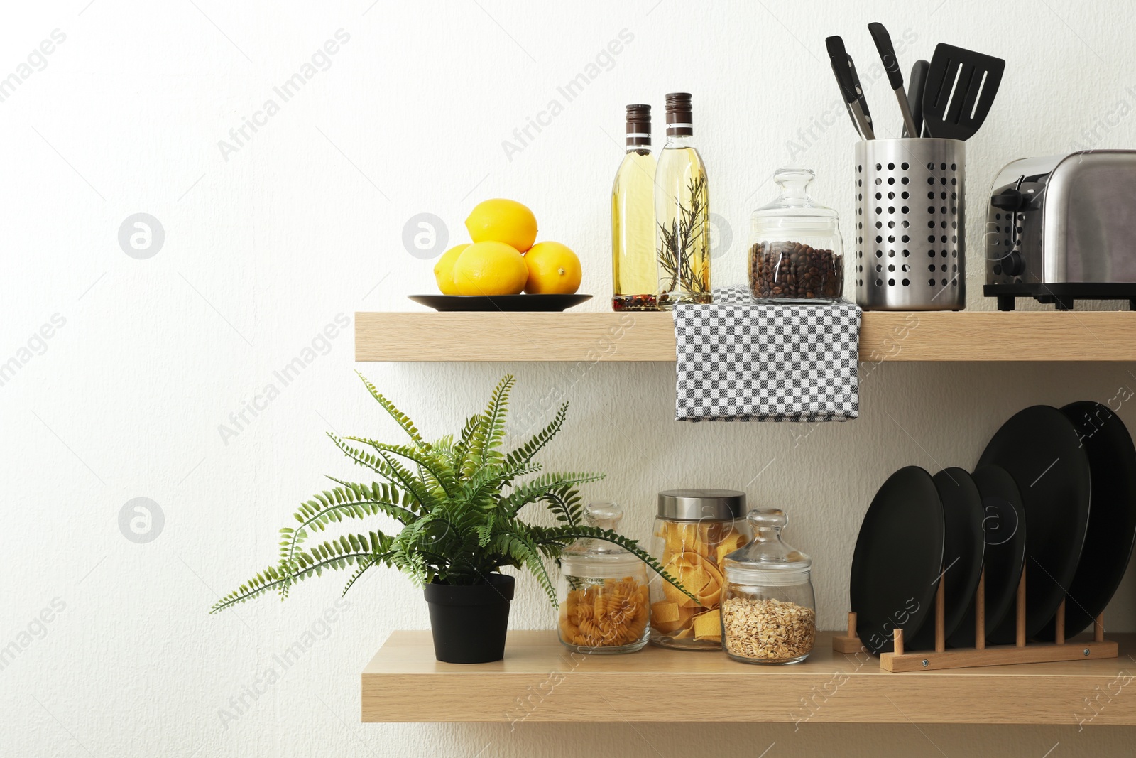 Photo of Wooden shelves with dishware and products on white wall. Kitchen interior idea