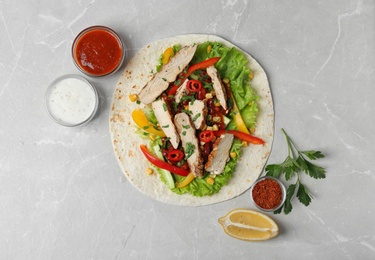 Delicious tortilla with meat on light table, flat lay