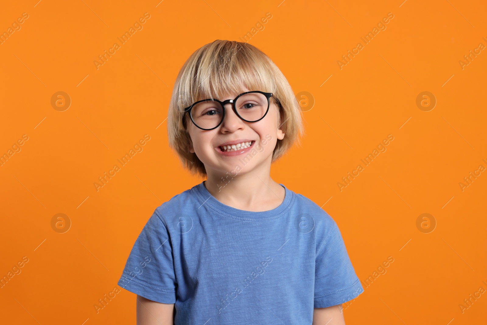 Photo of Cute little boy wearing glasses on orange background