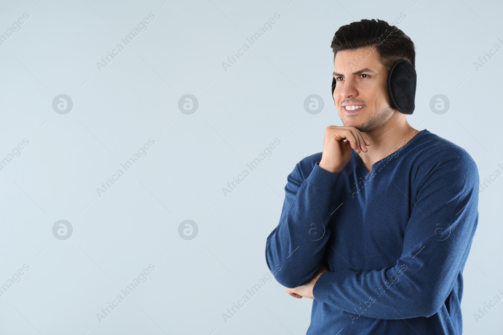 Photo of Man wearing stylish earmuffs on light background. Space for text