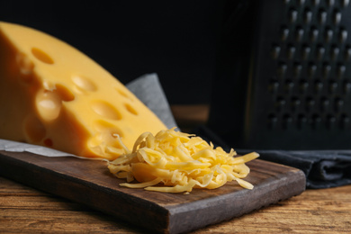 Photo of Tasty grated cheese on wooden table, closeup