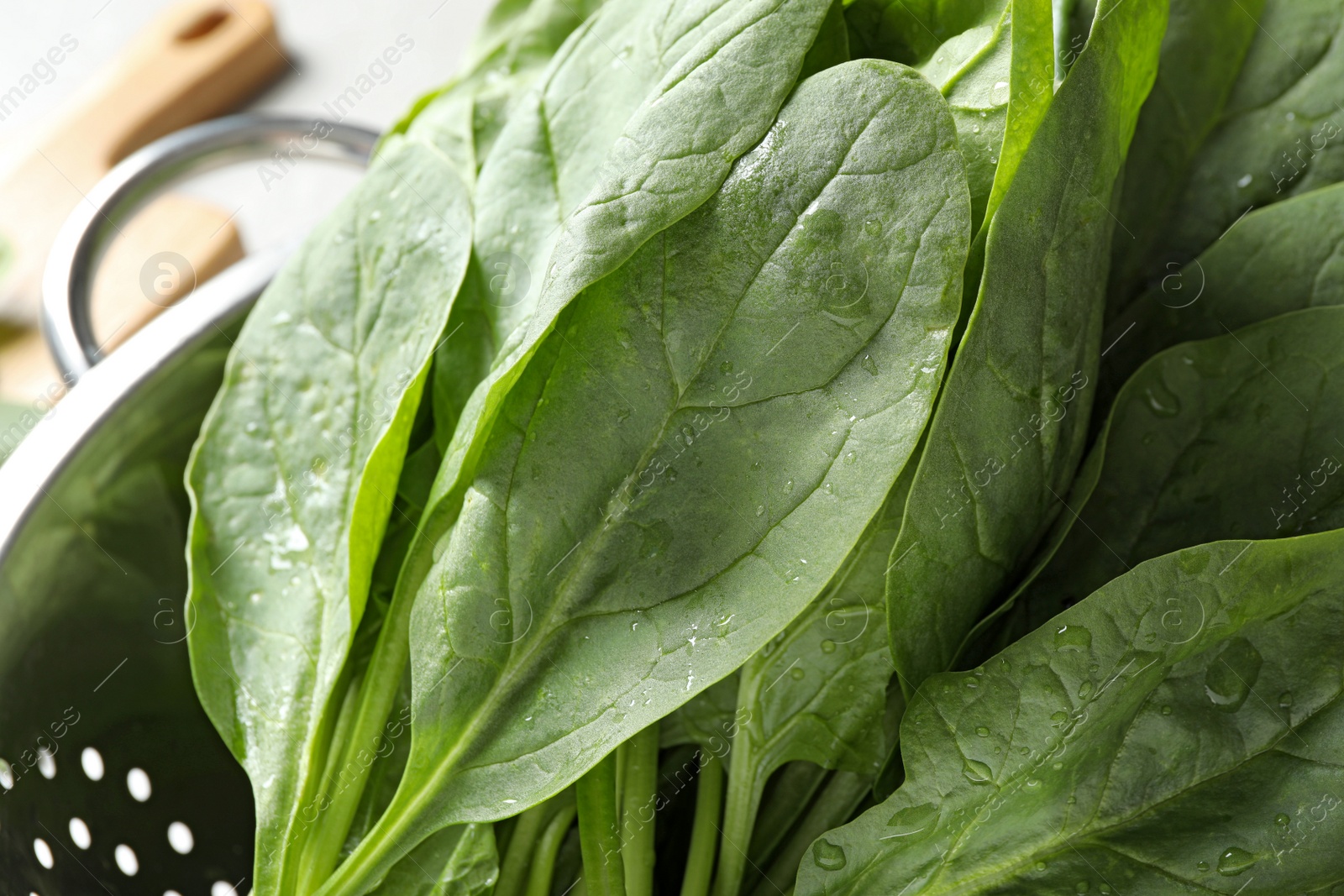 Photo of Colander with fresh green healthy spinach, closeup view