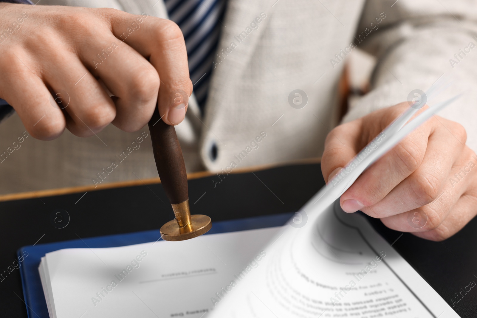 Photo of Notary stamping document at table, closeup view