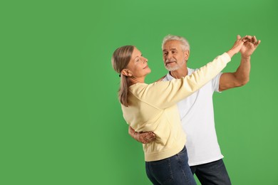 Photo of Senior couple dancing together on green background, space for text