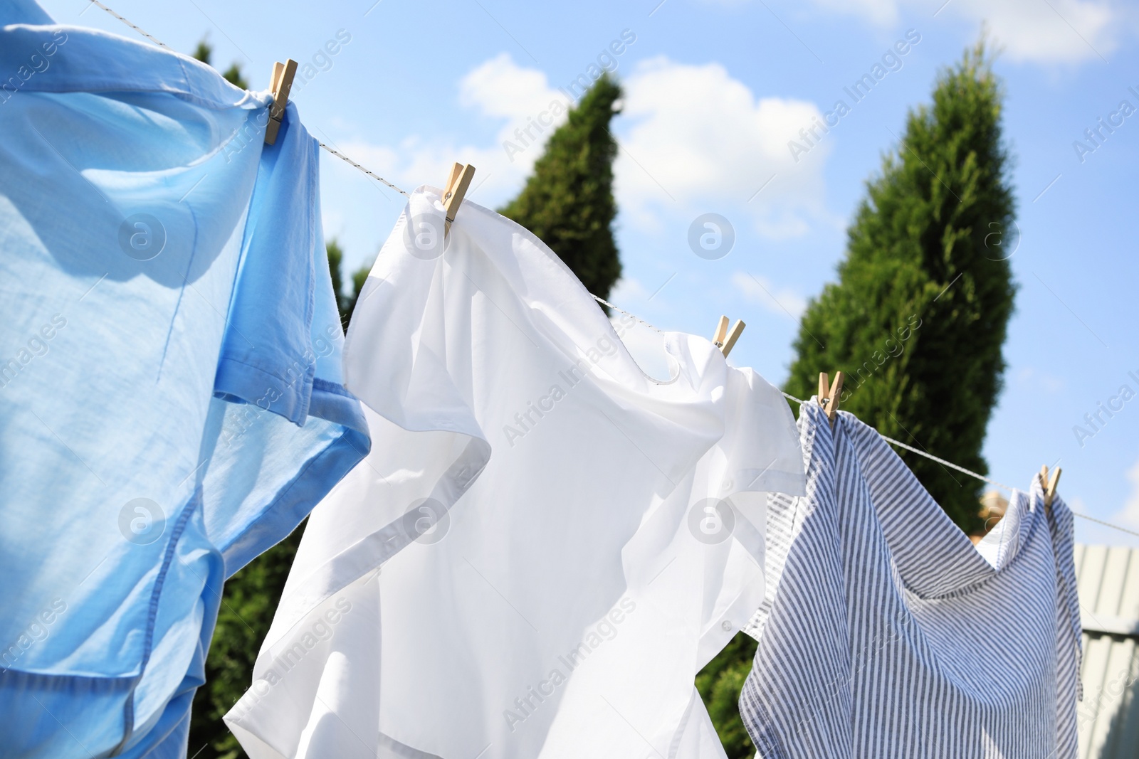 Photo of Clean clothes hanging on washing line outdoors. Drying laundry