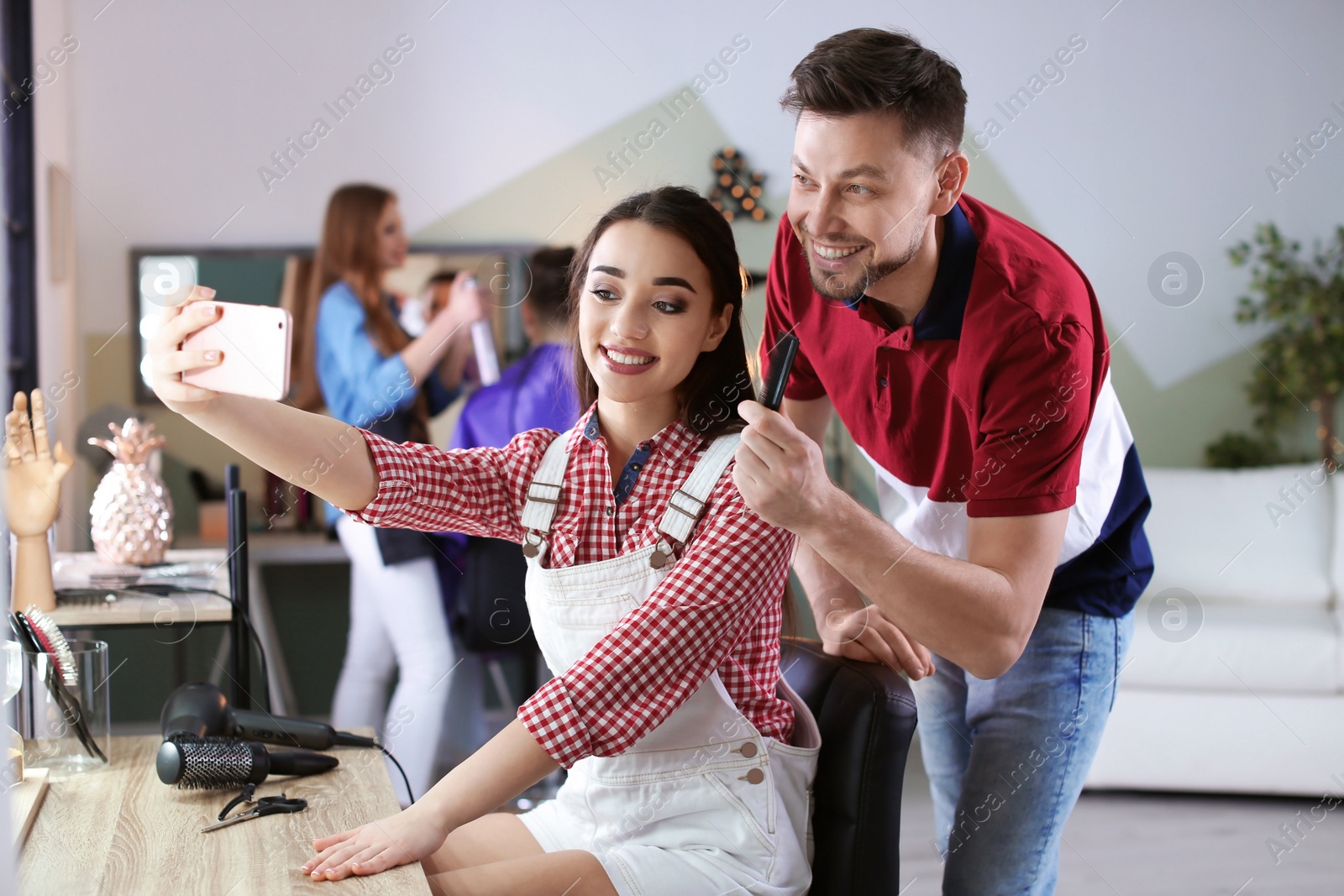 Photo of Hairdresser with happy client taking selfie in beauty salon