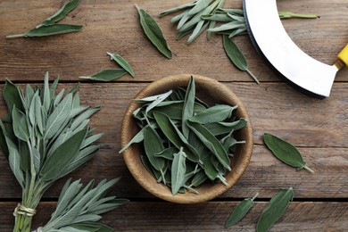 Photo of Fresh green sage with bowl and cutter on wooden table, flat lay