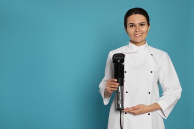 Chef holding sous vide cooker on light blue background. Space for text