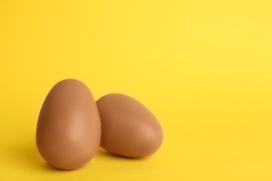 Sweet chocolate eggs on yellow background. Space for text