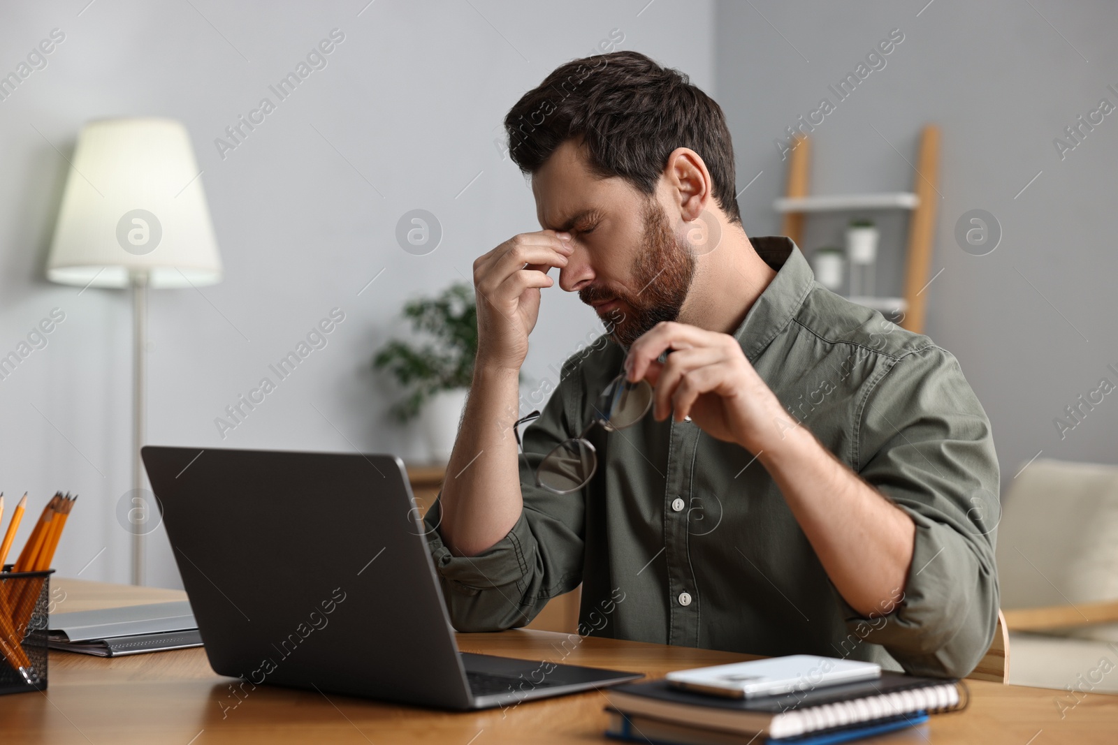 Photo of Tired man suffering from headache at workplace