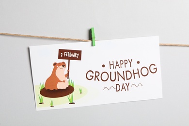 Photo of Happy Groundhog Day greeting card hanging on light background