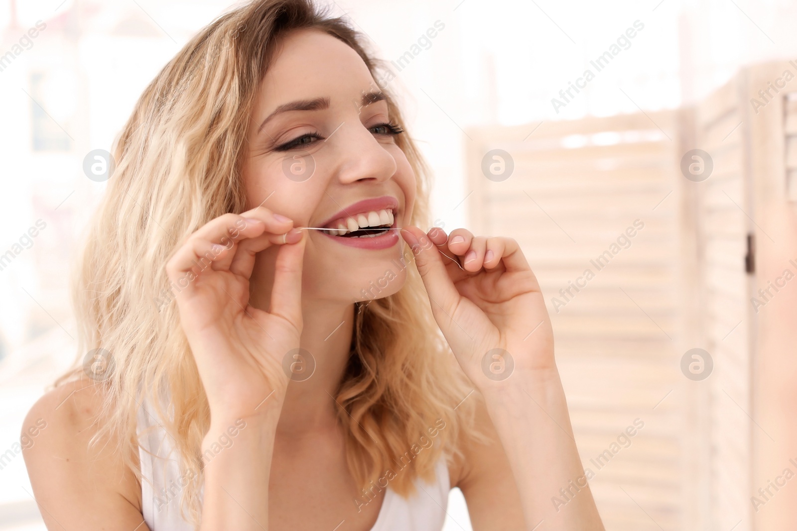 Photo of Young woman flossing her teeth in bathroom