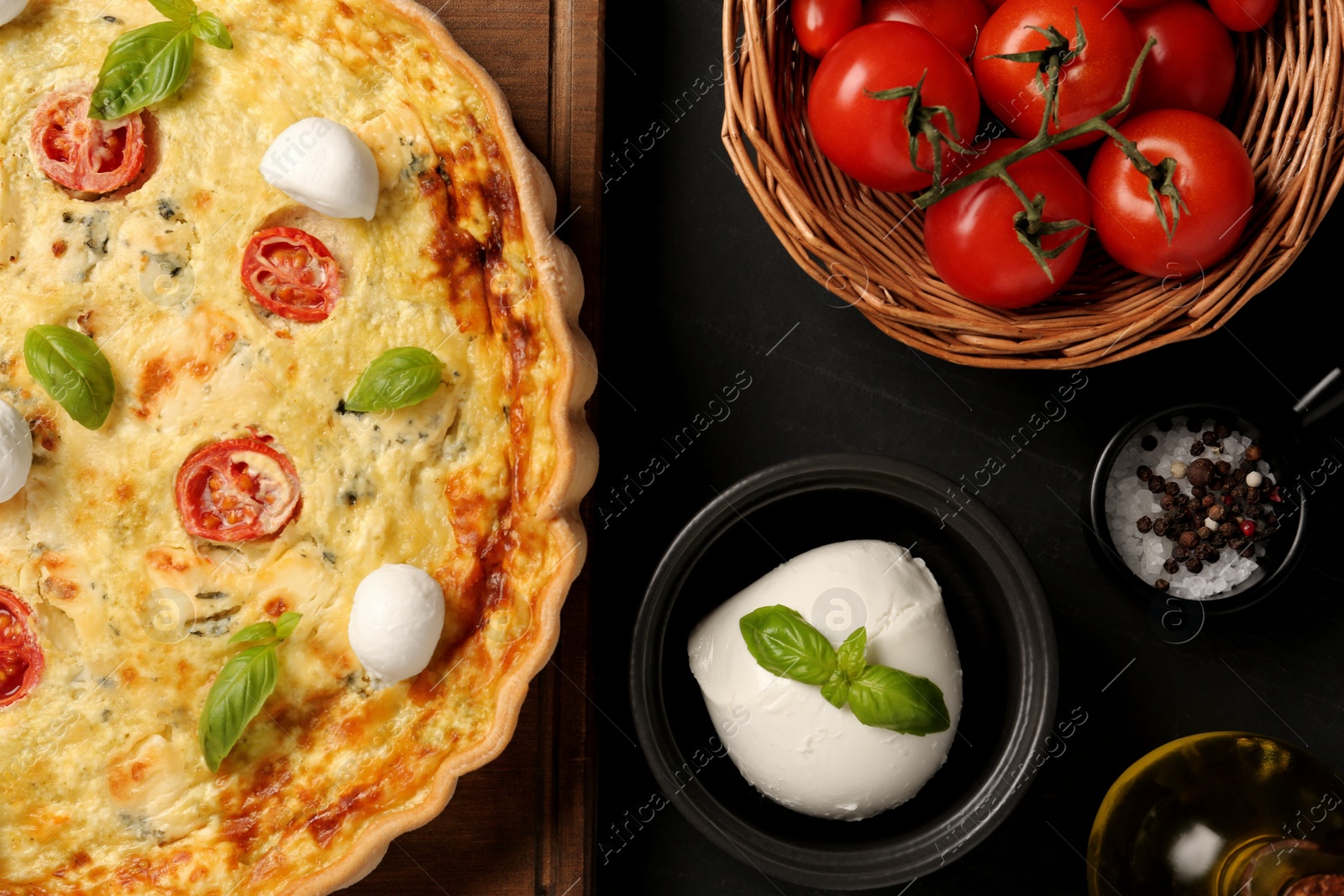 Photo of Delicious homemade cheese quiche and ingredients on black table, flat lay