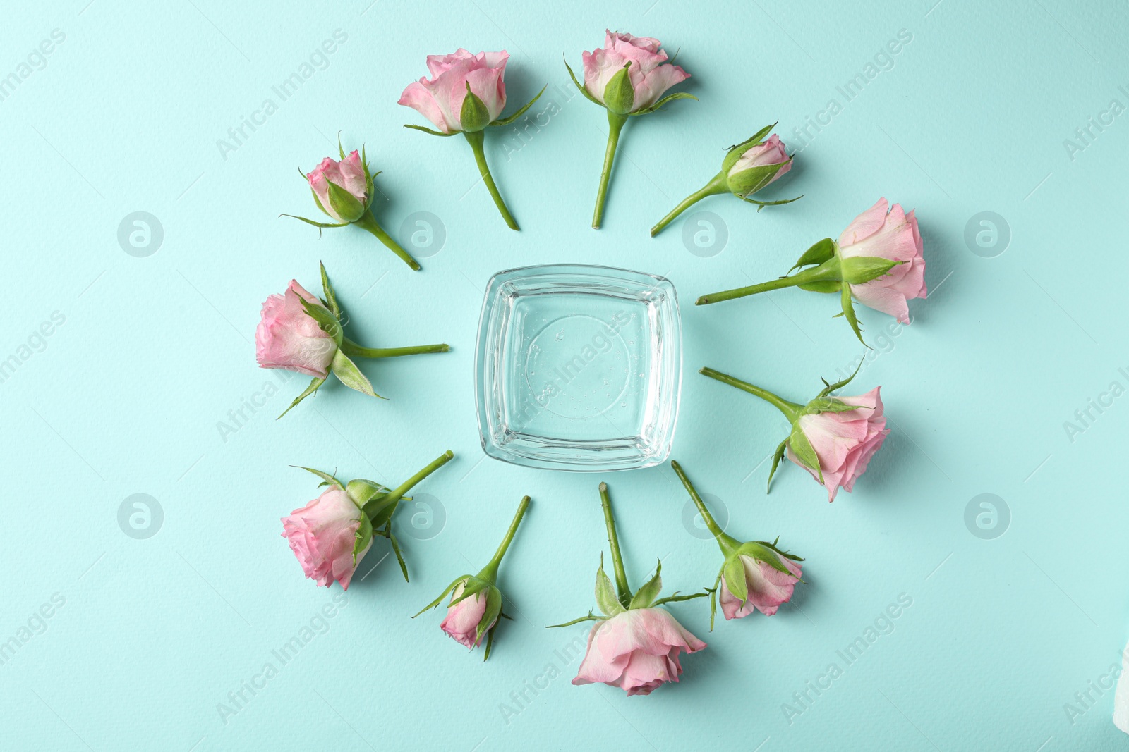 Photo of Flat lay composition with cosmetic gel and beautiful flowers on light blue background
